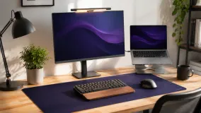 A workspace showing a few affordable desk upgrades: a light bar, a laptop stand, and a desk mat