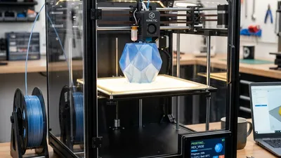 A modern, sleek, high-quality CoreXY 3D printer sitting on a clean workshop desk.