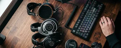 A person contemplating whether to buy a new pair of headphones surrounded by old tech