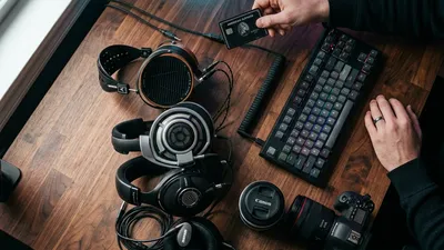 A person contemplating whether to buy a new pair of headphones surrounded by old tech