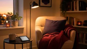A cozy reading nook with a comfy chair, warm lamp, blanket, and a small shelf of books
