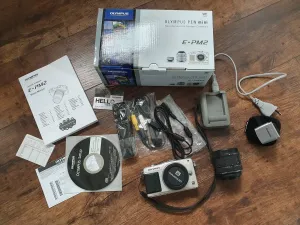 Olympus PEN E-PM2 camera on a desk in a modern workspace
