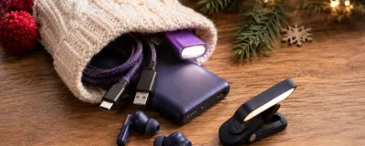 A festive stocking filled with small tech gadgets like earbuds, cables, and a mini light