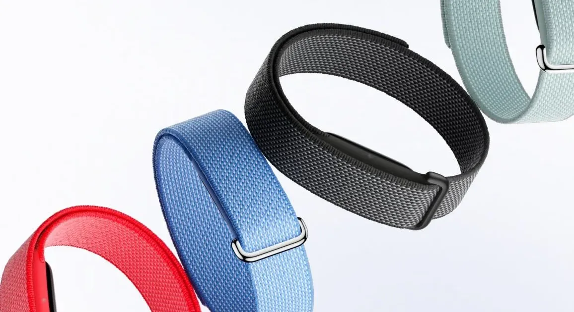 Comparison photo showing the slim Fitbit Air next to a WHOOP 4.0 strap on a wooden table