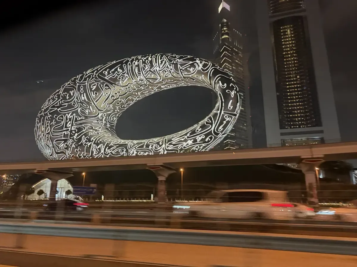 The Museum of the Future lit up at night — Arabic calligraphy covers the entire torus-shaped building