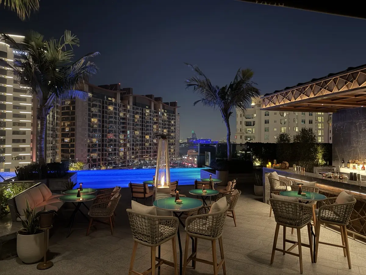 Rüya's rooftop terrace at night — pool, palm trees, and Dubai skyline views